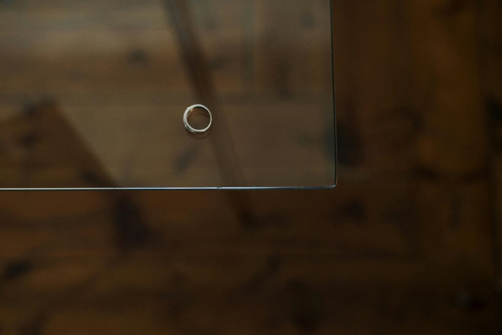 A single engagement ring rests on a glass table, symbolizing contemplation.